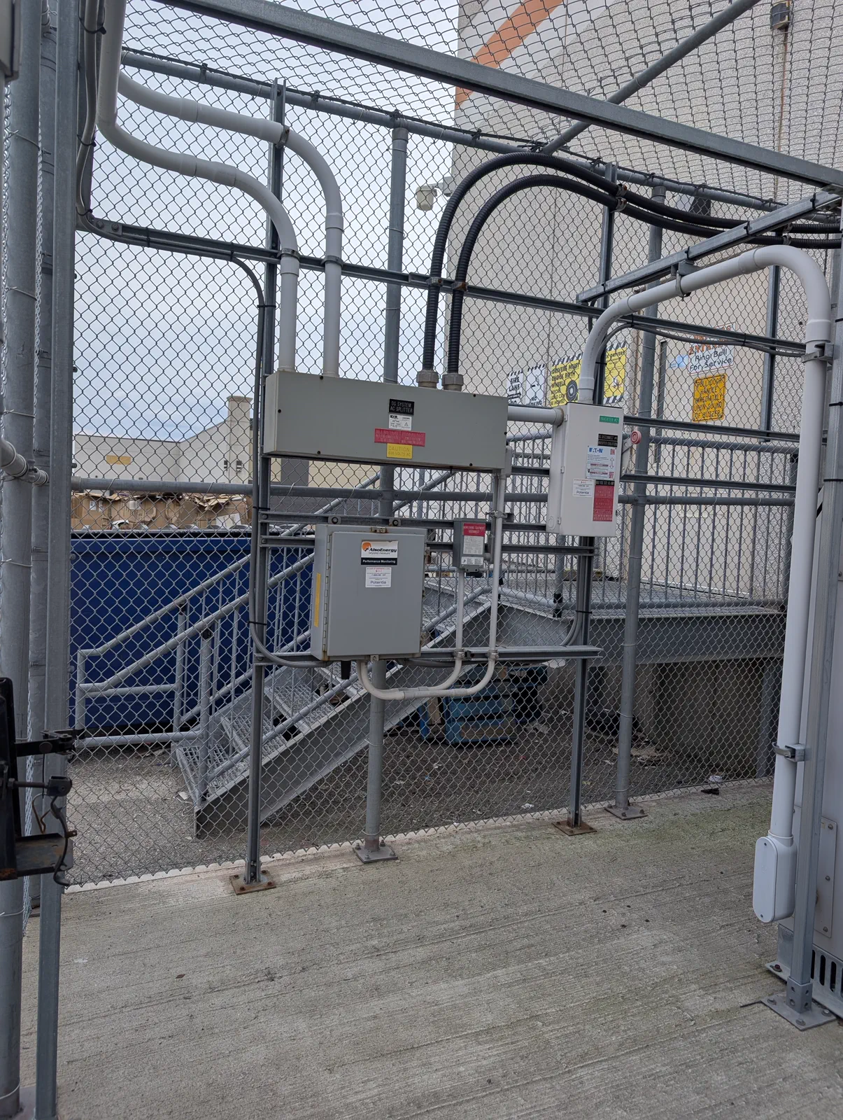 Commercial exterior disconnects and electrical equipment installed behind a fence.